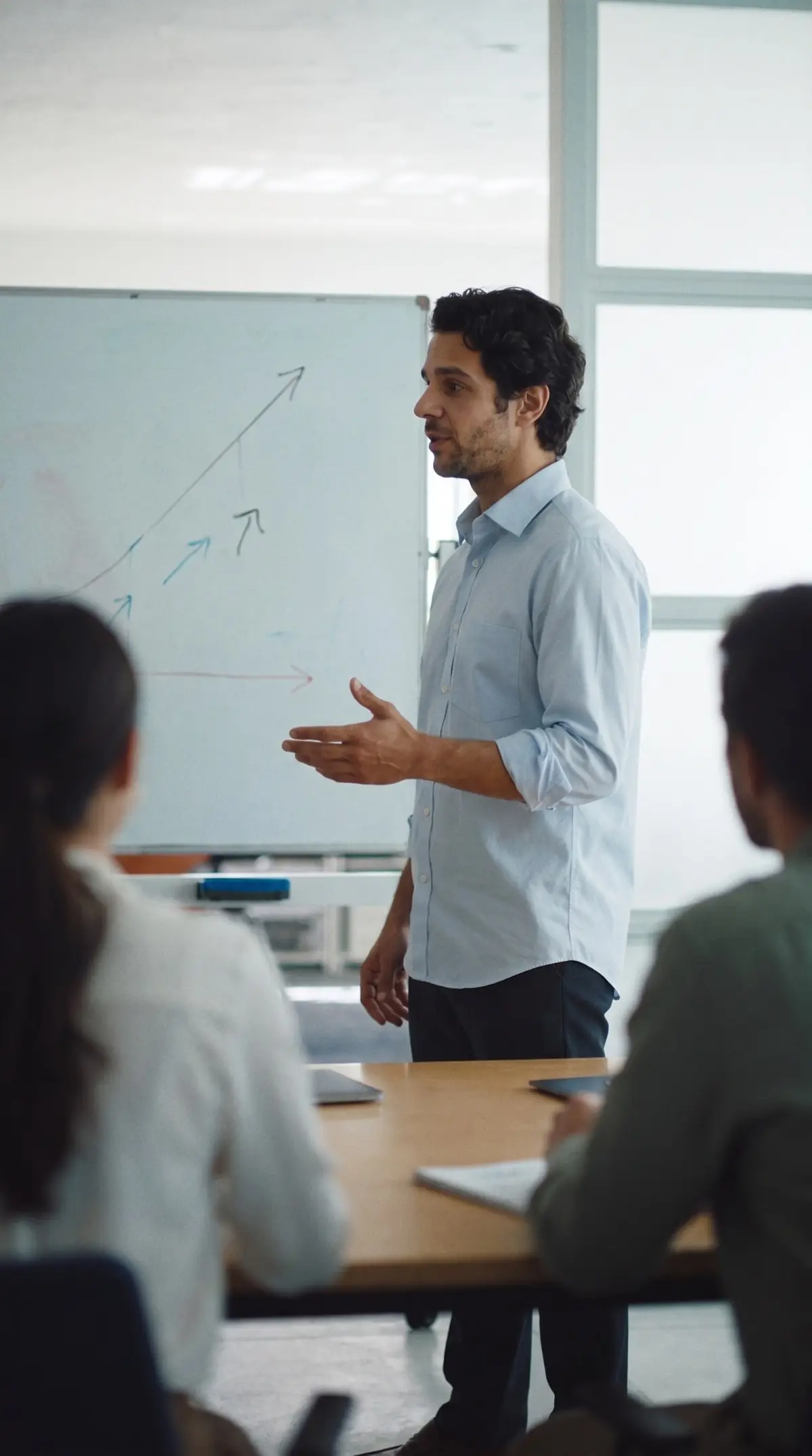 Joven líder explica un plan en el pizarrón a su equipo