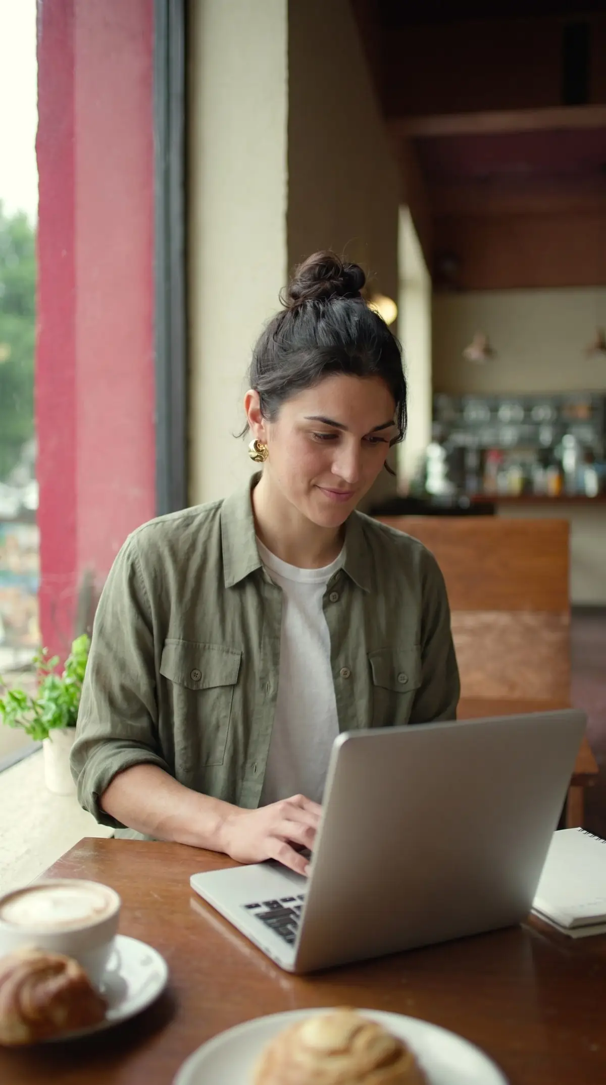 Joven trabajando con su laptop en su proyecto desde una cafetería